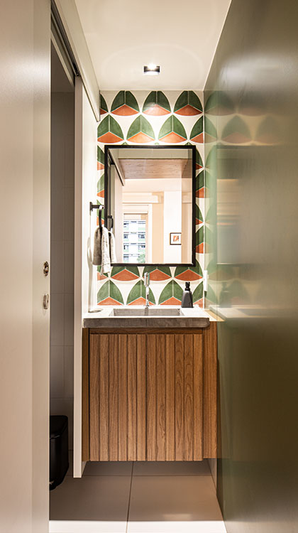 Lavabo com gabinete de madeira, pia de concreto e detalhes no espelho em preto